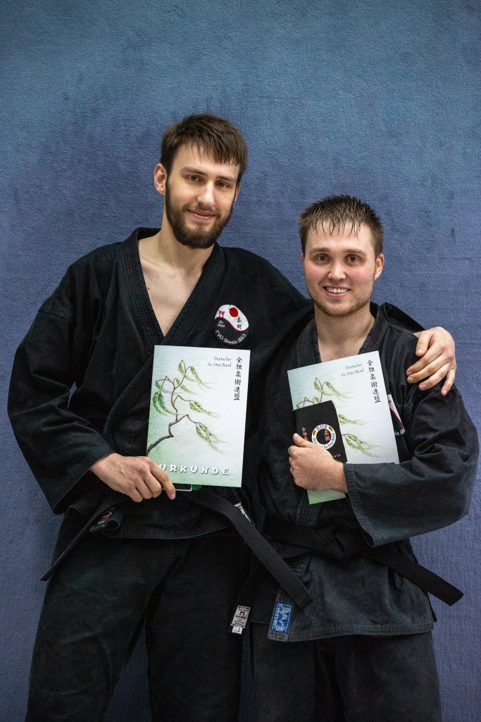 Zei Trainer Arm in Arm mit Urkunden in der Hand